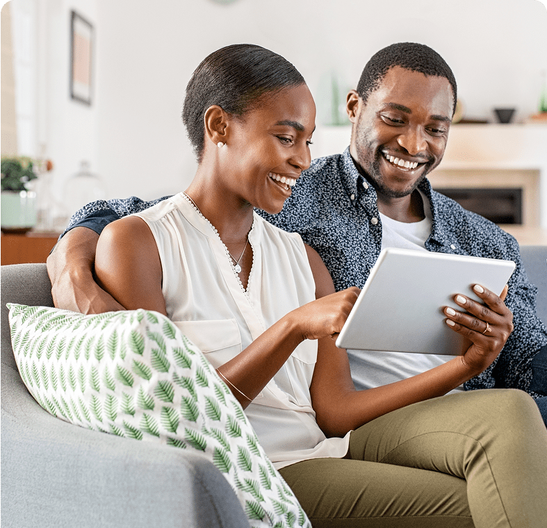 Couple smiling while using a tablet together.